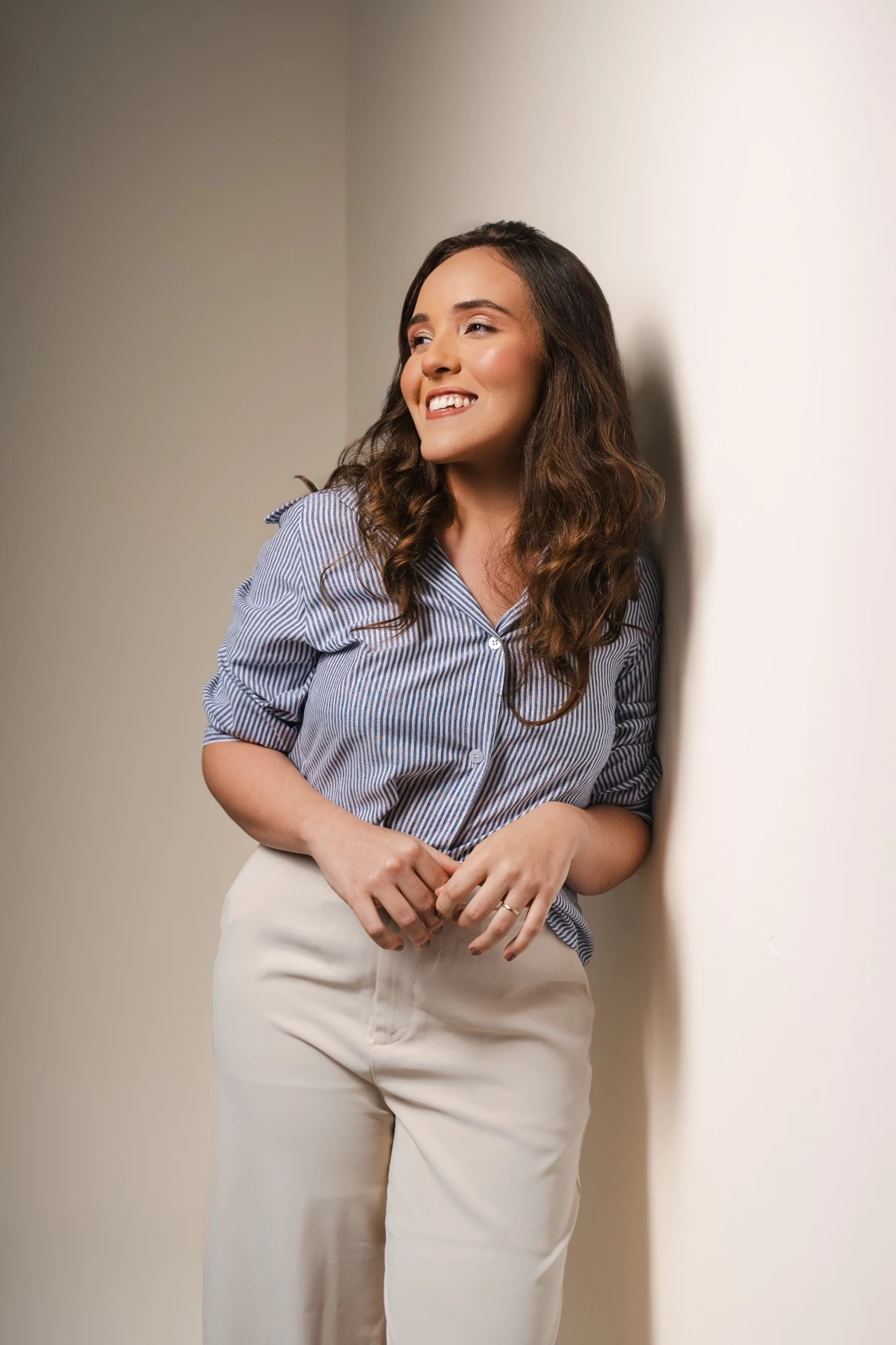 Emanoela Cavalcante em pé, olhando para o lado, em retrato profissional